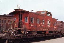 Caboose X-20, blocked up on Trailer On Flat Car (TOFC) car.  No trucks on caboose